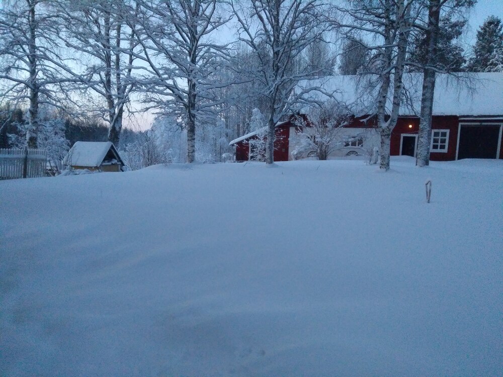 Bostadshuset och ladan i vinterskrud, skymning
